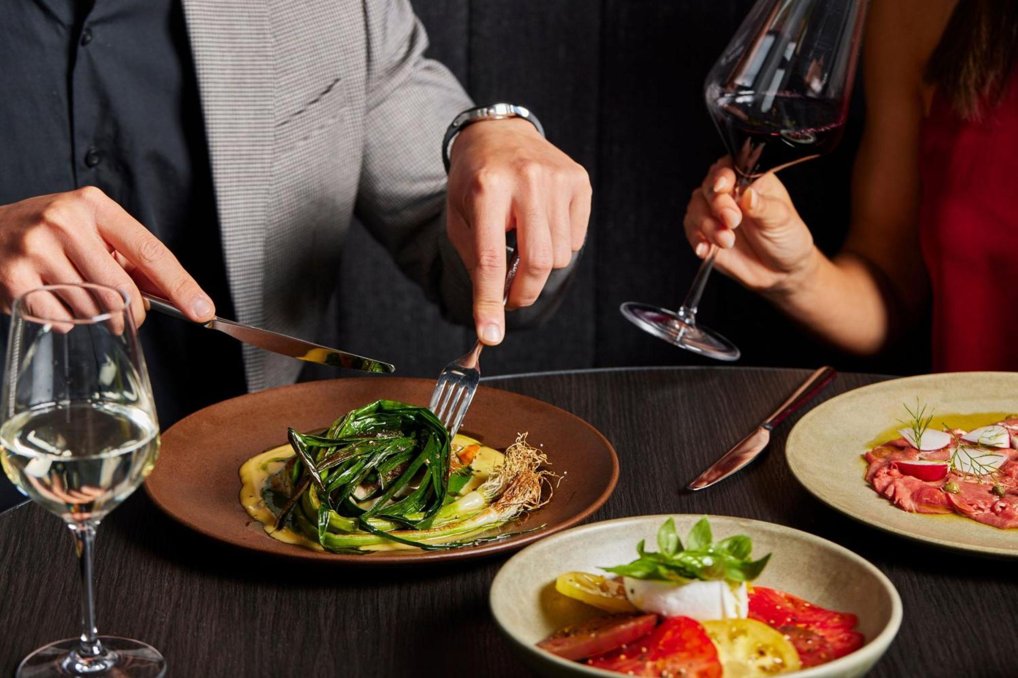 Melbourne Marriott Hotel Docklands Exteriör bild A man using a knife and fork to cut into a meal